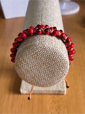 This handmade Huayruro seed bracelet features striking red and black seeds.